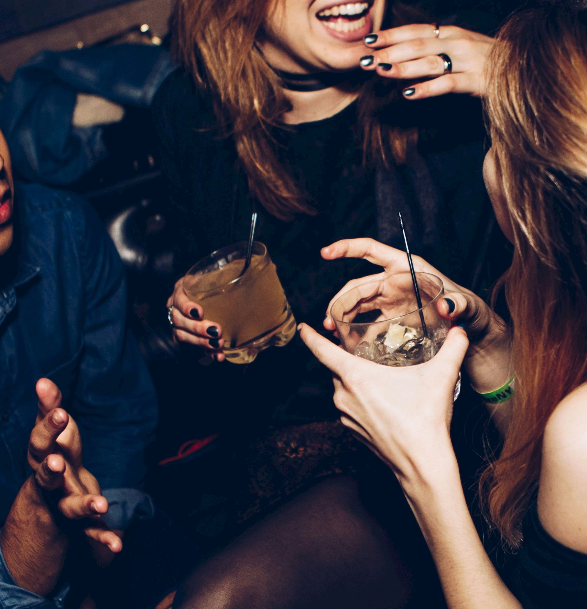 People are enjoying a social gathering, holding drinks with straws, and engaging in conversation and laughter.